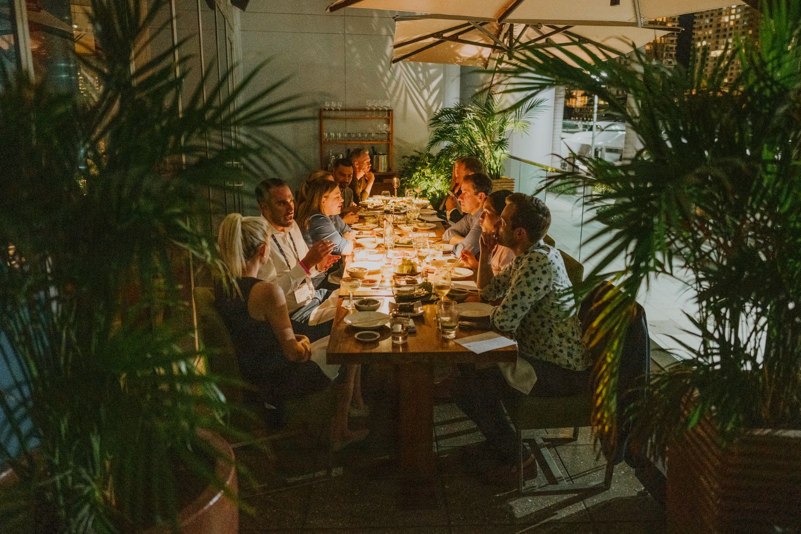 A long table lit under the palms on a terrace at night